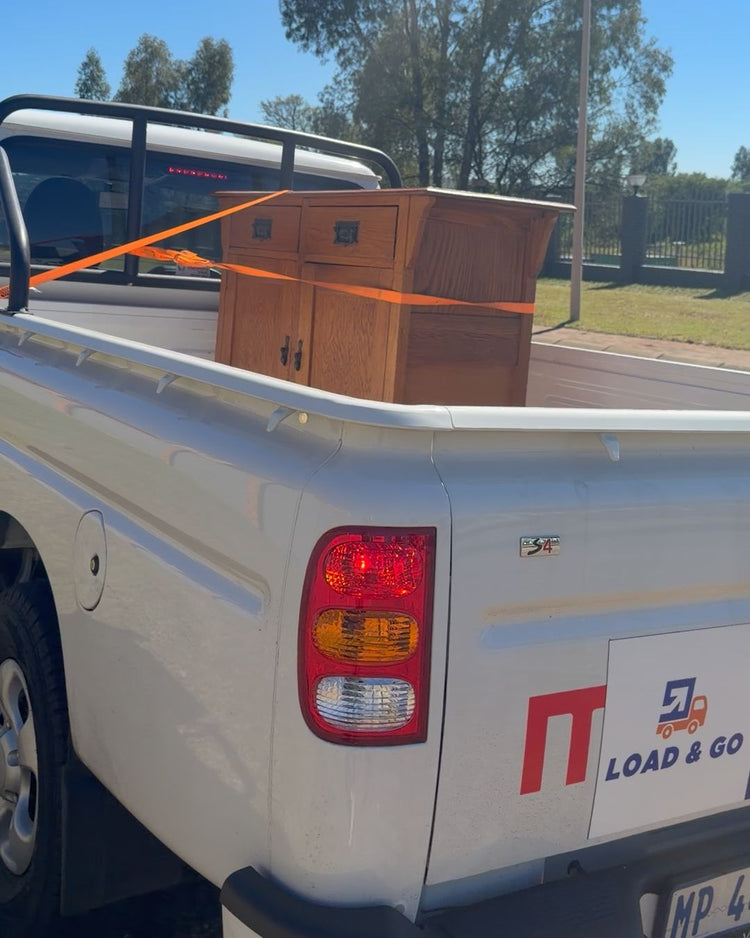 A wooden cabinet strapped down in the load bed of the Load & Go bakkie