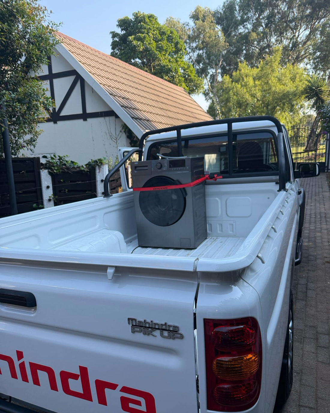 A washing machine strapped down in the load bed of the Mahindra bakkie